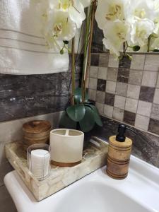 lavabo en el baño con bandeja con platos y flores en Luny apartment en Ruse