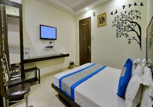 Hotel University Stay @ A1Rooms في نيودلهي: غرفة نوم مع سرير وتلفزيون على الحائط