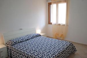 Nuovissimo appartamento a due passi dalla spiaggia di Maladroxia C61 في Maladroxia: غرفة نوم بسرير لحاف ازرق ونافذة