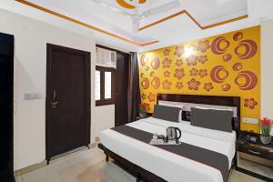 - une chambre avec un grand lit et un mur jaune dans l'établissement OYO Hotel Lotus, à New Delhi