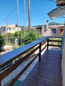 a wooden walkway leading to a porch with an umbrella at Thanos Guesthouse Corfu in Áyioi Dhéka