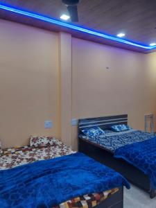 duas camas num quarto com luzes azuis na parede em Shri KrishnMohini Home stay em Matura