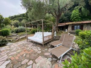 a bed and two chairs on a stone patio at Maison Du Reve Scario in Scario