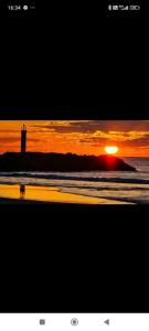 a sunset on a beach with a lighthouse in the ocean at studio au cap d'agde dans les pinèdes in Cap d'Agde