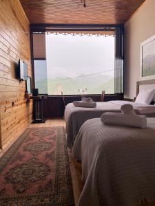 two beds in a room with a large window at AYVADERE 102 Karadeniz kus cenneti dağ manzaralı in Araklı