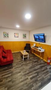 ein Wohnzimmer mit einem roten Sofa und einem Flachbild-TV in der Unterkunft Radio Navarino in Puerto Williams