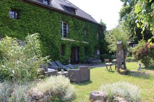 a green building with chairs in the yard at Maison de Charme "Le Moulin d'Hagenthal" - Chambre Baroque in Hagenthal-le-Bas