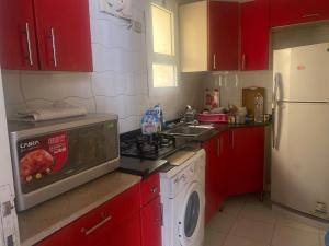 eine Küche mit roten Schränken und einem Herd mit Backofen in der Unterkunft A cosy Apartment just for you to relax in Madinat as-Sadis min Uktubar