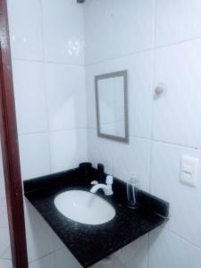 La salle de bains est pourvue d'un lavabo noir et d'un miroir. dans l'établissement Apartamento espaçoso, à Cabo Frio