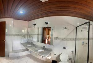 a bathroom with two sinks and a mirror and a toilet at Pousada Atalaia Capivari in Campos do Jordão