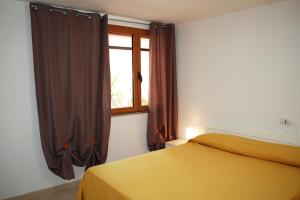 - une chambre avec un lit jaune et une fenêtre dans l'établissement Appartamento con veranda e aria condizionata a Maladroxia C62, à Maladroscia
