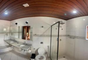 uma casa de banho com um WC, um lavatório e um espelho. em Pousada Atalaia Capivari em Campos do Jordão