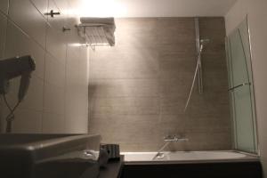 a bathroom with a shower and a tub and a sink at Hotel Astel in De Haan