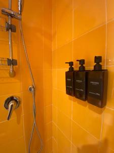 y baño con ducha y pared de azulejos de color naranja. en Appartamento Al Teatro en Livorno
