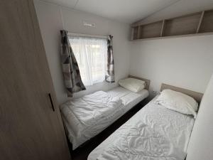 two beds in a small room with a window at Camping Oasis Middelkerke 2-slpk caravan 'New Tropical' in Ostend