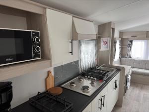 a small kitchen with a stove and a microwave at Camping Oasis Middelkerke 2-slpk caravan 'New Tropical' in Ostend