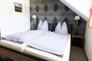 Hotel Herres Alte Metzgerei في ليوين: غرفة نوم بسريرين مع وسائد مخططة زرقاء وبيضاء