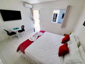 Pousada Peromar في ماراغوغي: غرفة نوم مع سرير أبيض كبير مع وسائد حمراء