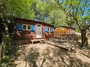 une cabane en rondins avec une table de pique-nique et un parasol dans l'établissement Camp des Gorges - Camping Nature, à Vallon-Pont-dʼArc