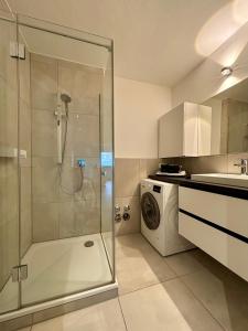 uma casa de banho com um chuveiro e uma máquina de lavar roupa em Leo‘s MUNICH Apartment em Munique