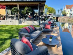 eine Terrasse mit Sofas, Tischen und einem Pool in der Unterkunft Hotel & Restaurant Fackelgarten Plau am See in Plau am See