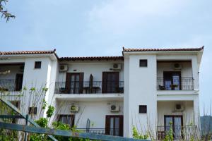 a white building with balconies and a fence at Hotel Defkalion in Álli Meriá