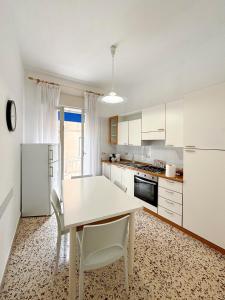 uma cozinha com armários brancos e uma mesa e cadeiras em bed Cammareri em Trapani