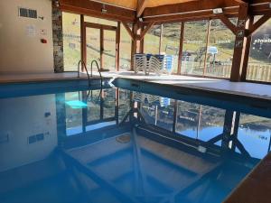a swimming pool in a building with a view at GUZET-Pyrénées-Pied des pistes in Ustou