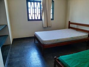 a bedroom with two beds and a window at Hospedagem Familiar in Piúma