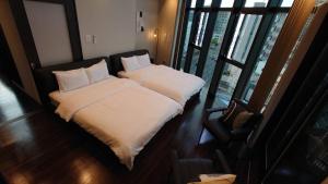 a bedroom with two beds with white blankets and pillows at Neighbor's Penthouse 竹屋 in Hiroshima