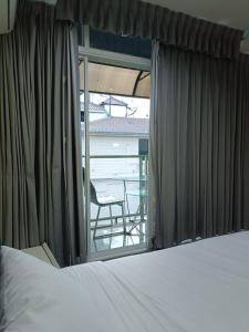 a bedroom with a bed and a window with a chair at Del Mar Rooms in Pattaya South