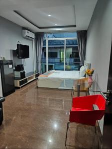 a living room with a bed and a red chair at Del Mar Rooms in Pattaya South