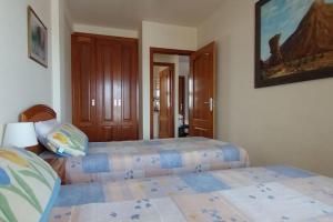 een slaapkamer met 2 bedden en een schilderij aan de muur bij 1-bedroom apartment with big terrace and ocean view in Los Cristianos in Los Cristianos