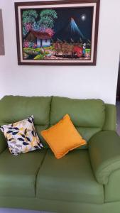 eine grüne Couch mit Kissen und ein Bild an der Wand in der Unterkunft Casa Bahía Ale, Bahía Ballena Uvita in Uvita