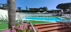 una piscina con sillas blancas y un montón de plantas en Hotel B&B Marina, en Paestum