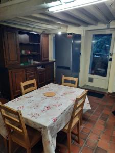 eine Küche mit einem Tisch und Stühlen sowie einem Kühlschrank in der Unterkunft La maison ancienne Auvergnate à Orléat in Orléat