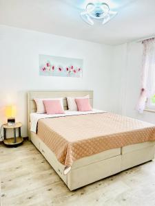 a white bedroom with a large bed with pink pillows at Holiday home Biondic in Krk
