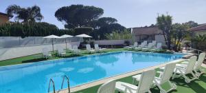 a swimming pool with white chairs and tables and umbrellas at Hotel B&B Marina in Paestum