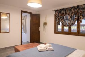 1 dormitorio con 1 cama con toallas en Alexandras guesthouse, en Neos Panteleimonas