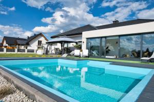 a swimming pool in front of a house at Dom z basenem & jacuzzi do 10 osób Zator Willa LuxHouse in Zator