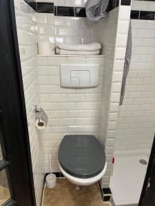 ein Bad mit einem schwarzen WC und weißen Fliesen in der Unterkunft FRIOUL in Marseille
