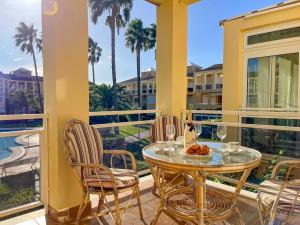balcone con tavolo in vetro, sedie e palme di 2-bed Apartament Rosaleda Monterey a Denia