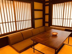a couch with a table in a room with windows at BUNA　KUSATSU in Kusatsu