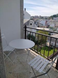 d'une table blanche et de deux chaises sur un balcon. dans l'établissement HR Liberdade, à Sarria