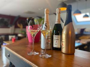 Tres botellas de vino y dos copas en una mesa. en Champagne Domaine Sacret - AY, en Épernay