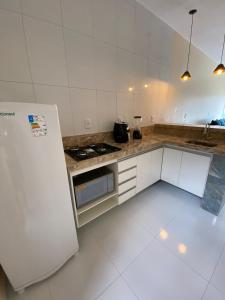 uma cozinha branca com um fogão e um frigorífico em Condomínio Farol das Dunas em Santo Amaro
