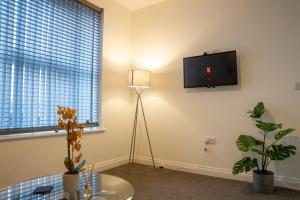 sala de estar con TV en la pared y mesa en Central 2-Bedroom Apartment in Kettering with Wifi by HP Accommodation en Kettering