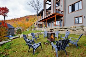 a group of chairs and a grill in front of a house at The Big Jack Chalet 33 Chemin Blanc by Les Chalets Alpins in Stoneham