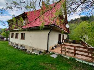 a house with a red roof and a wooden deck at Chata Pod Kwiatkiem in Zawoja