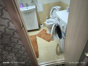 a bathroom with a toilet and a washing machine at Уютная квартира комфорт класса74 in Astana